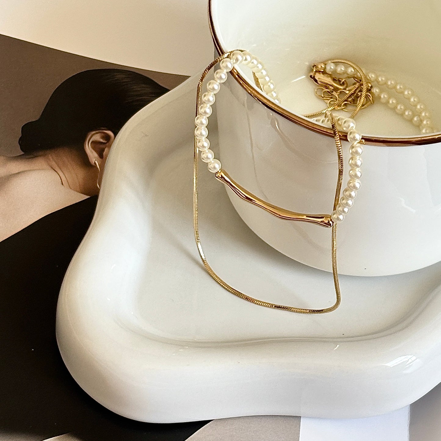 Pearl and gold bracelet on a white surface with a blurred person in the background
