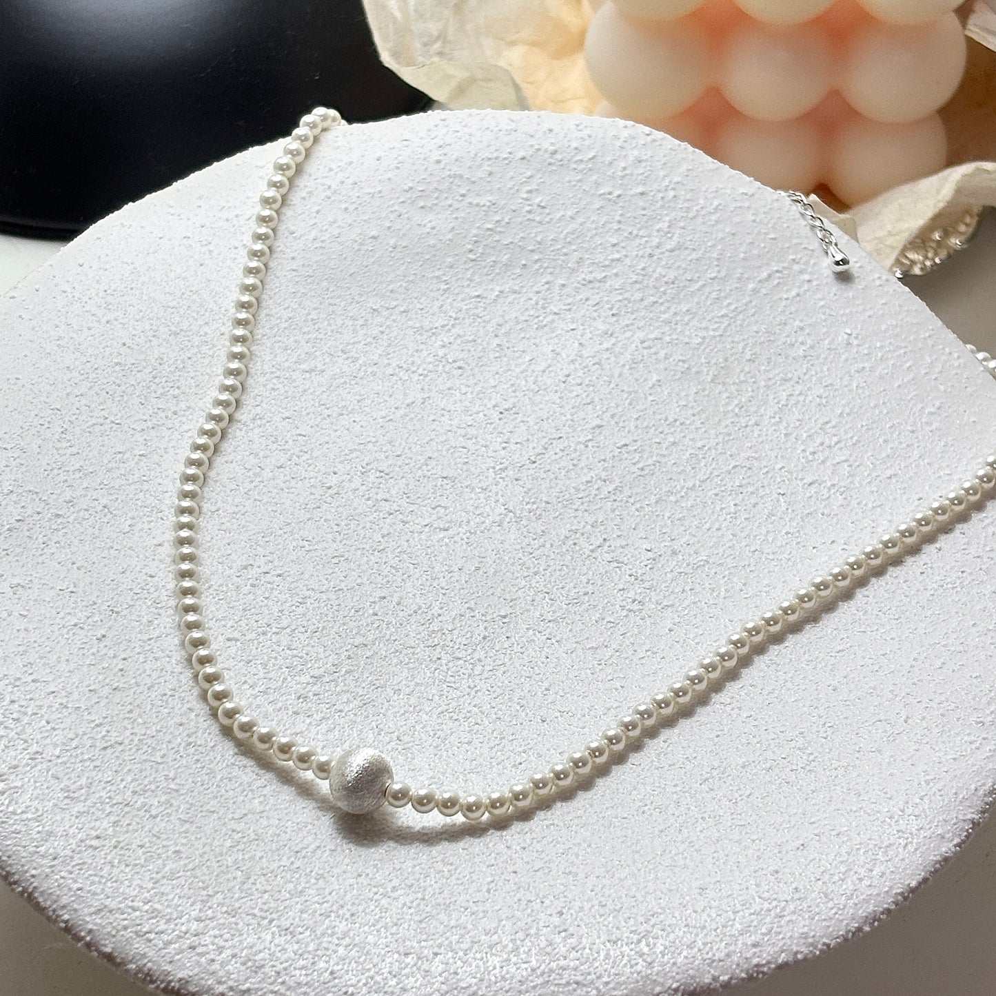 Pearl necklace on a textured white surface with soft focus background