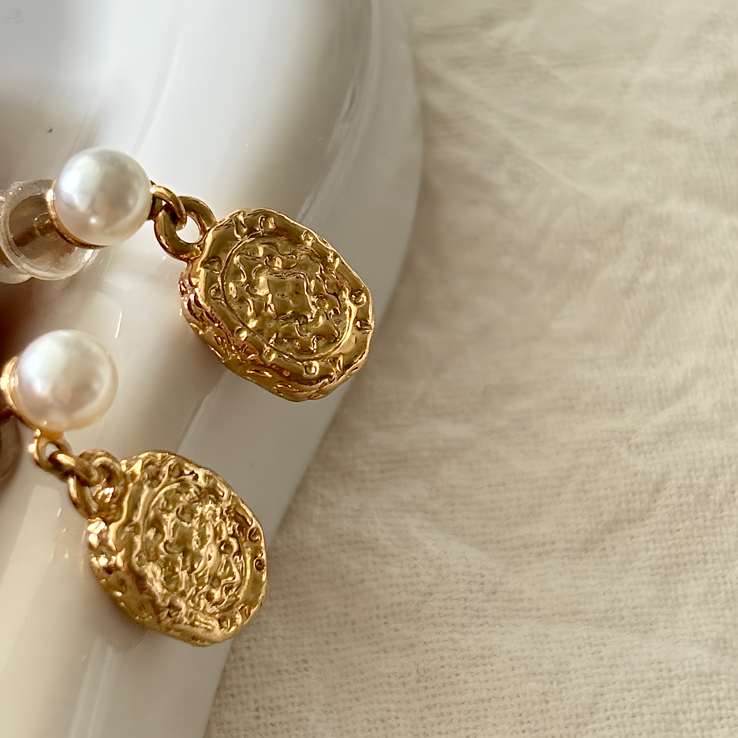 Gold earrings with pearl accents on a white surface