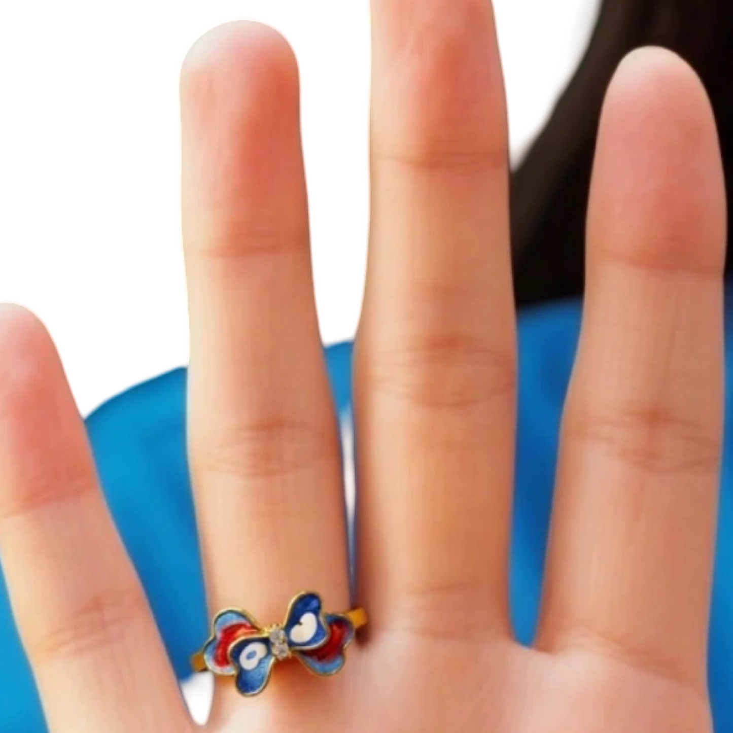Colorful butterfly ring on a person's finger with a blue background