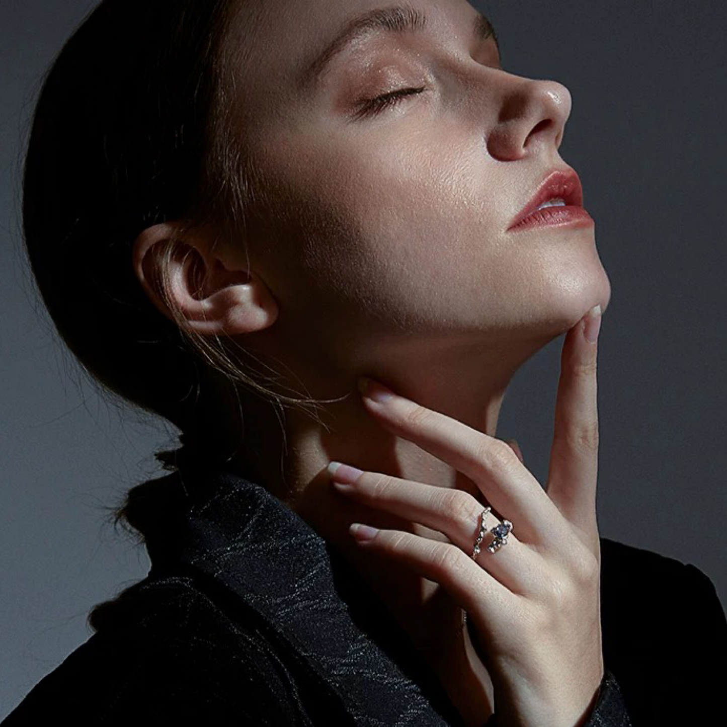 Woman wearing a diamond ring with a dark background