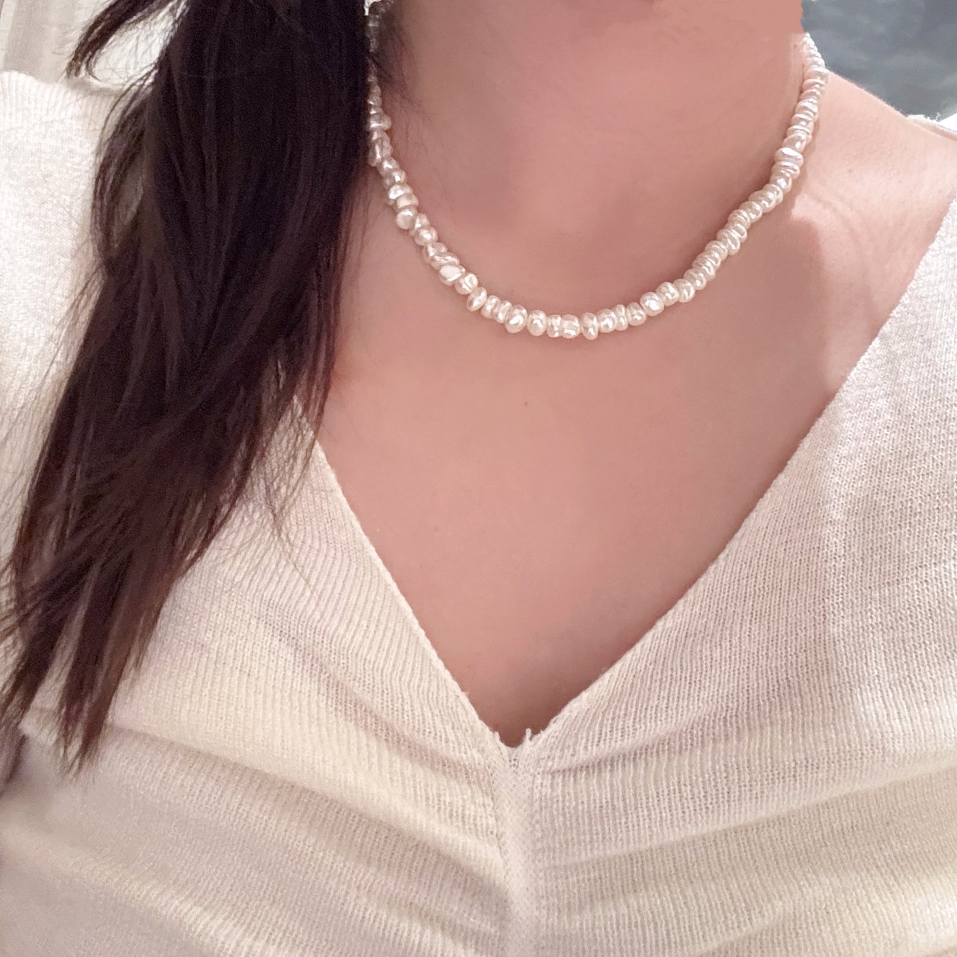 Pearl necklace worn by a person with a blurred background