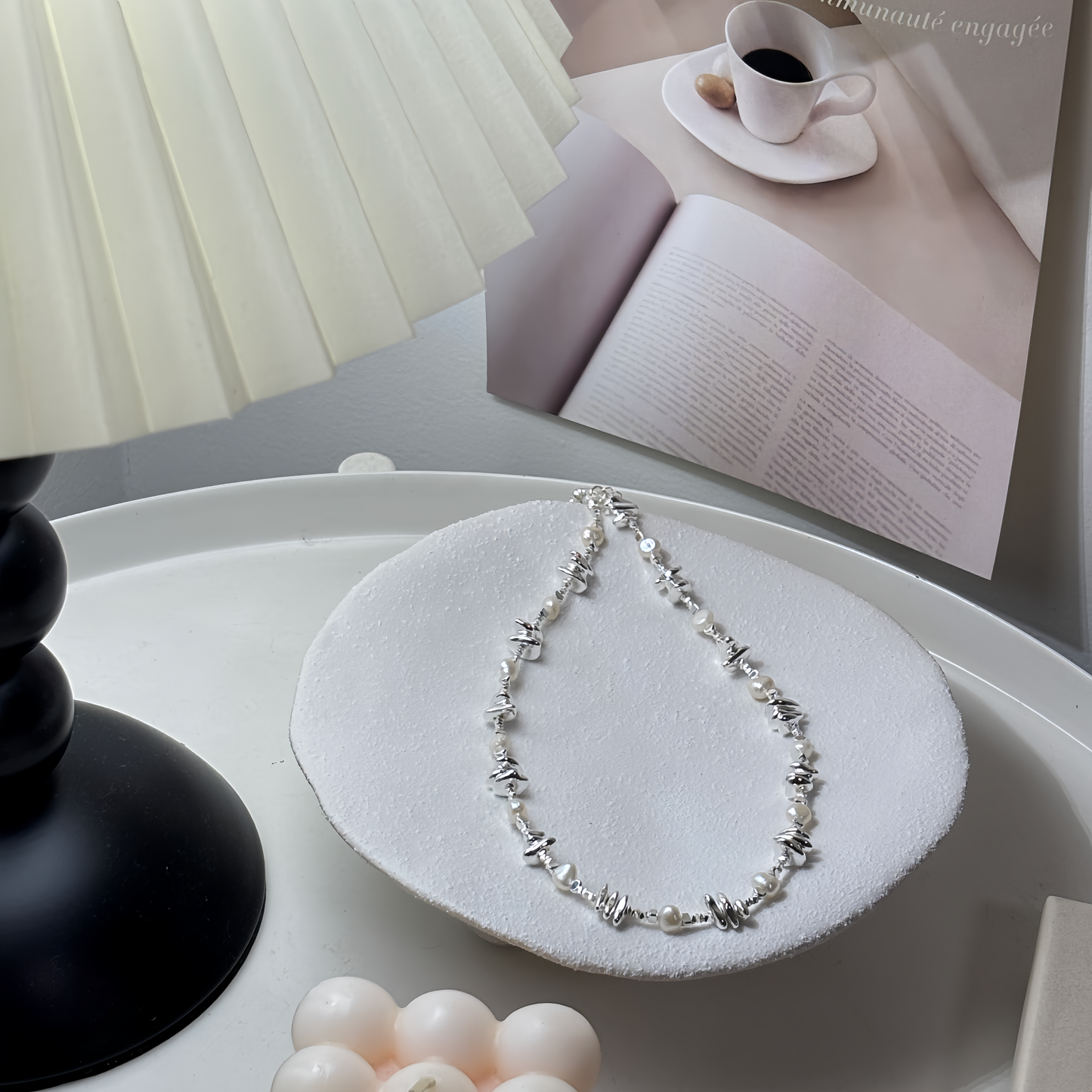 Necklace on a white dish with pearls and a book in the background