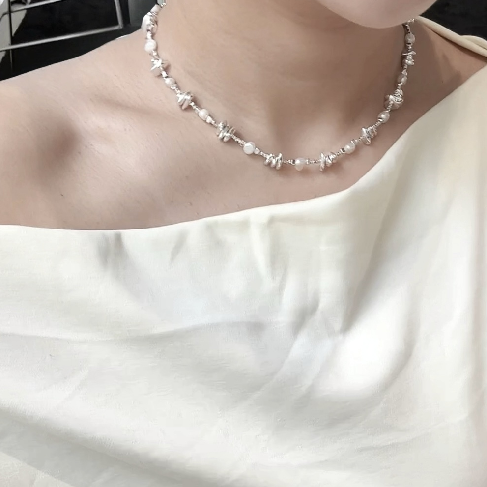 Pearl necklace worn by a person against a white background