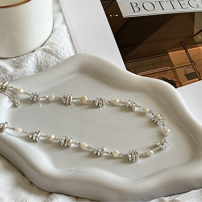 Pearl necklace on a white dish with 'Bottega' sign in the background