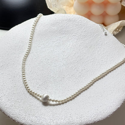 Pearl necklace on a textured white surface with soft focus background