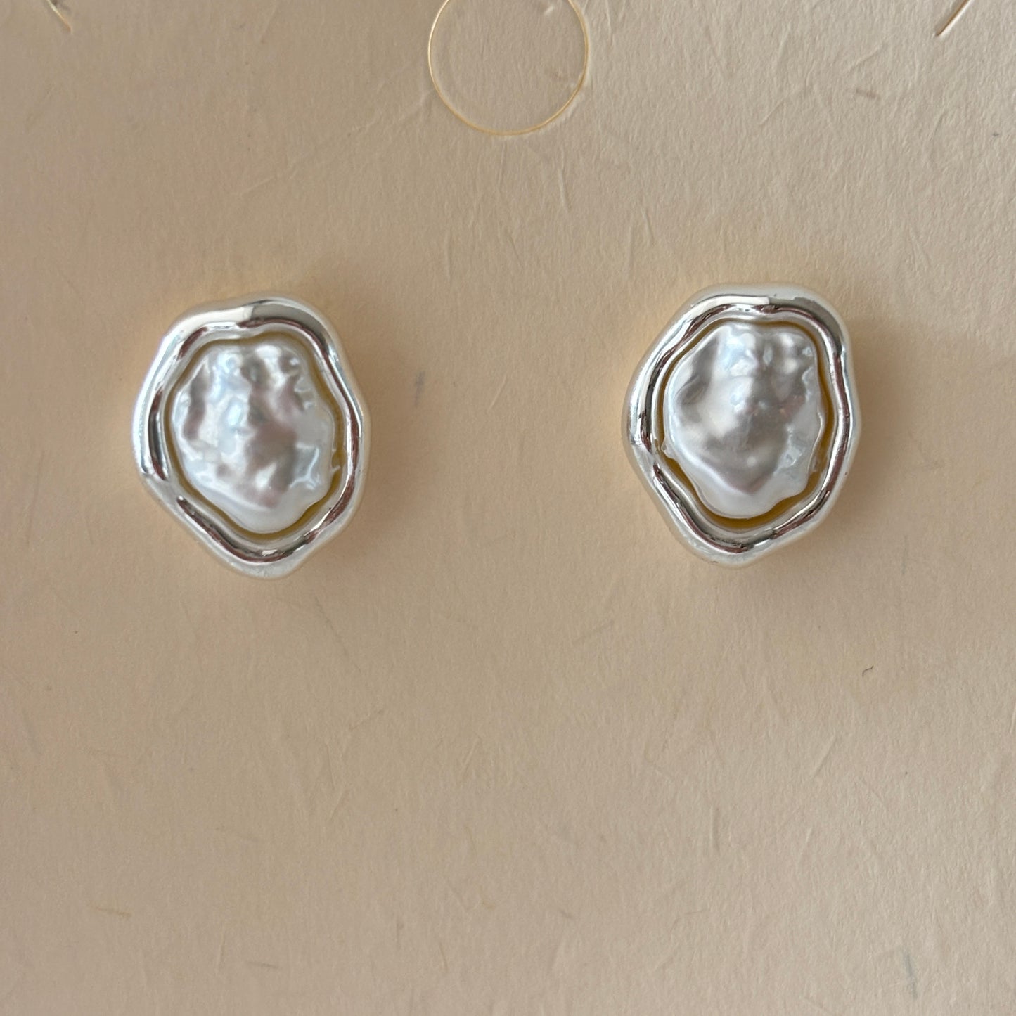 Pair of silver earrings with natural pearls on a beige background