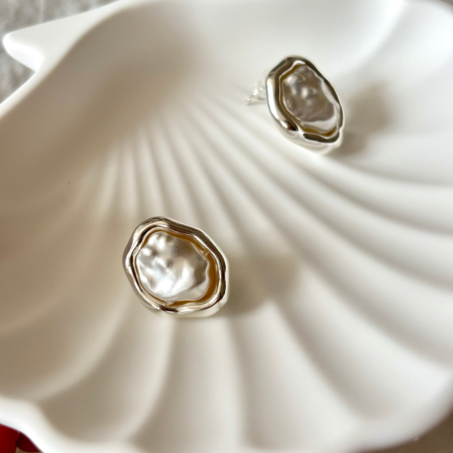 Silver earrings with a natural pearl design on a white shell background