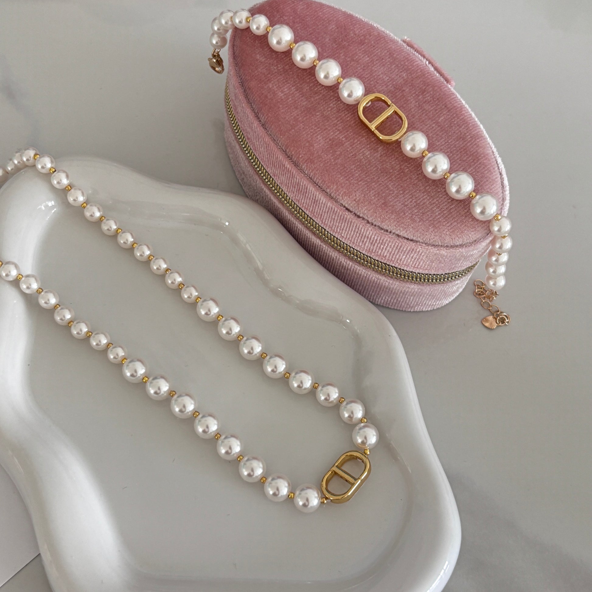 Pearl necklace with gold clasp on a pink velvet case on a white surface