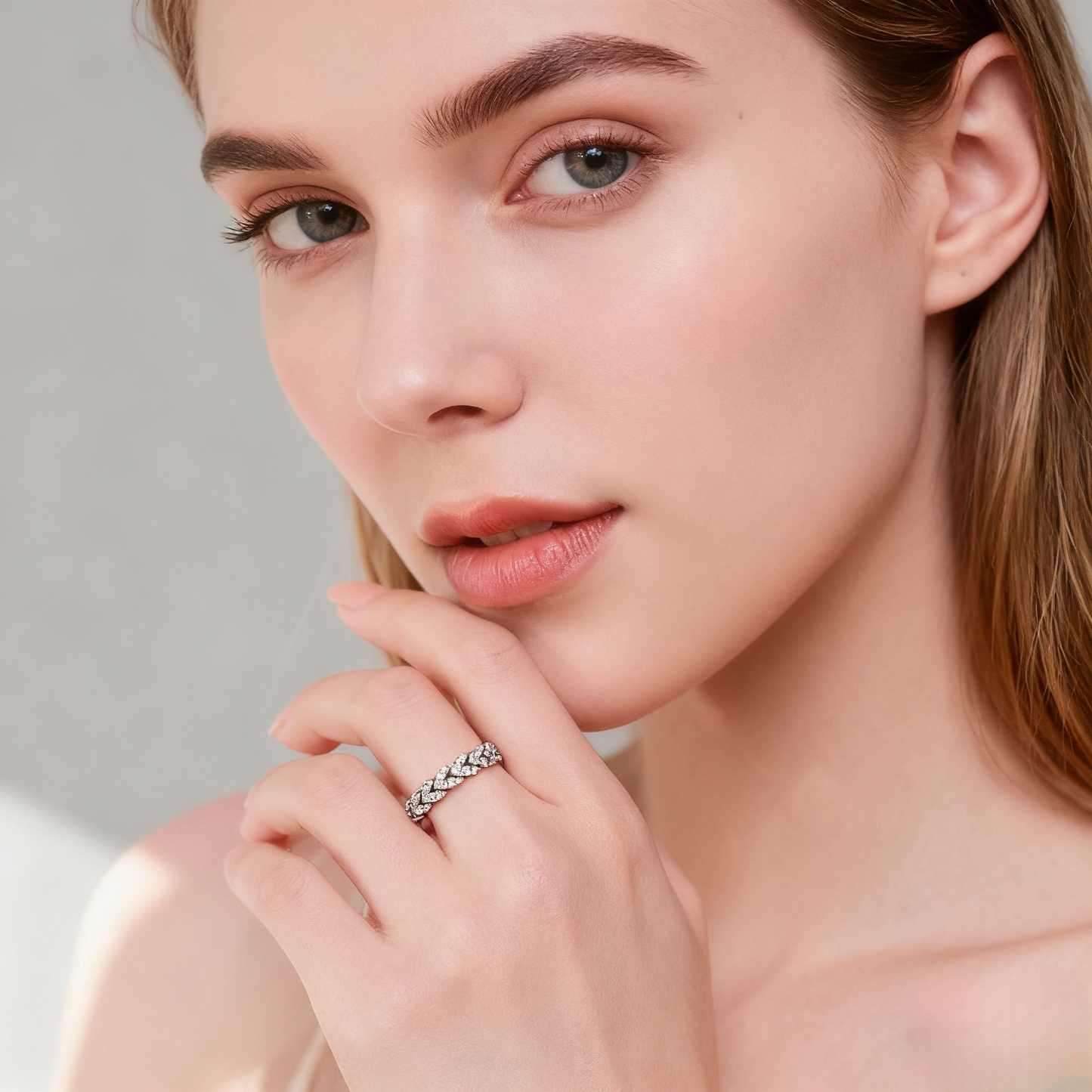 Close-up of a woman wearing a silver ring on a neutral background