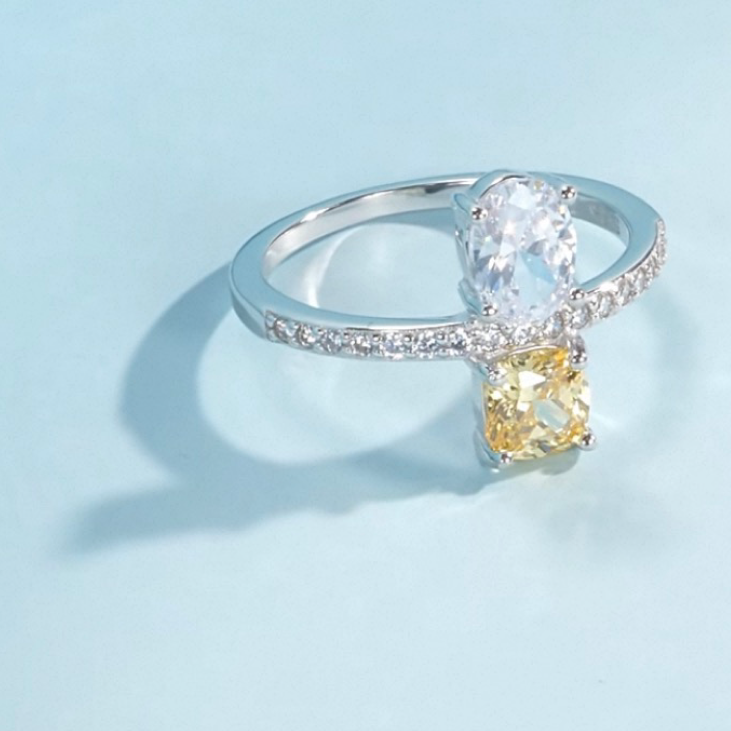 Silver ring with a yellow gemstone on a light blue background