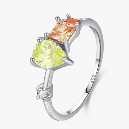 Silver ring with green and orange gemstones on a white background