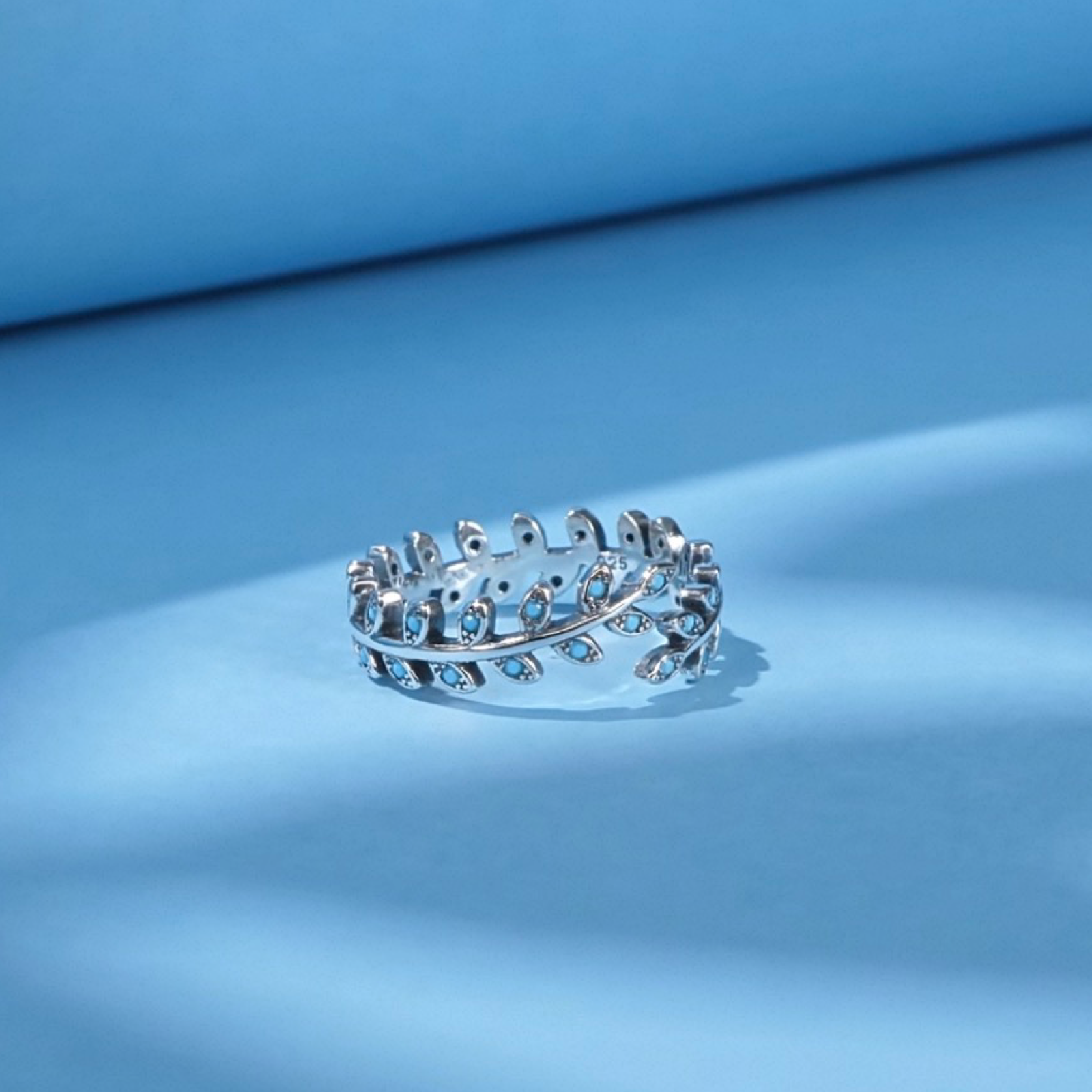 Silver ring with small stones on a blue surface