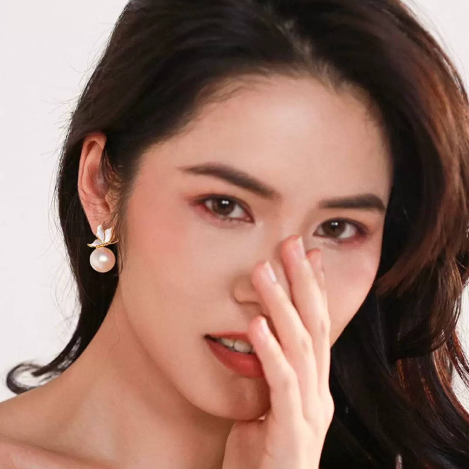 Close-up of a woman with a neutral expression, wearing earrings.