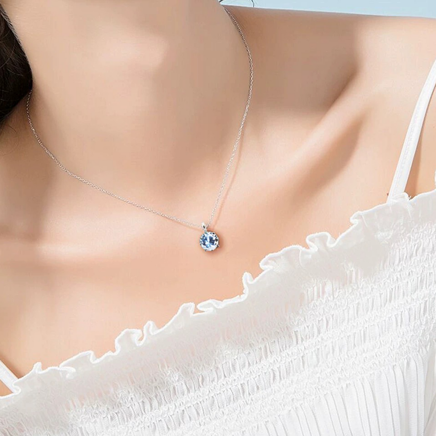 Necklace with a blue pendant on a model wearing a white top