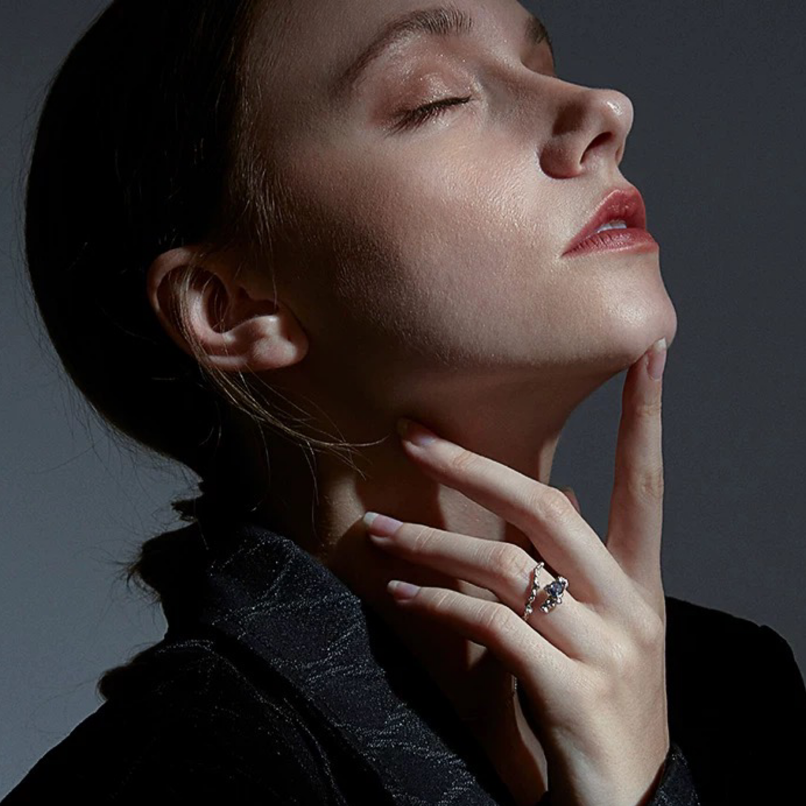 Woman wearing a diamond ring with a dark background