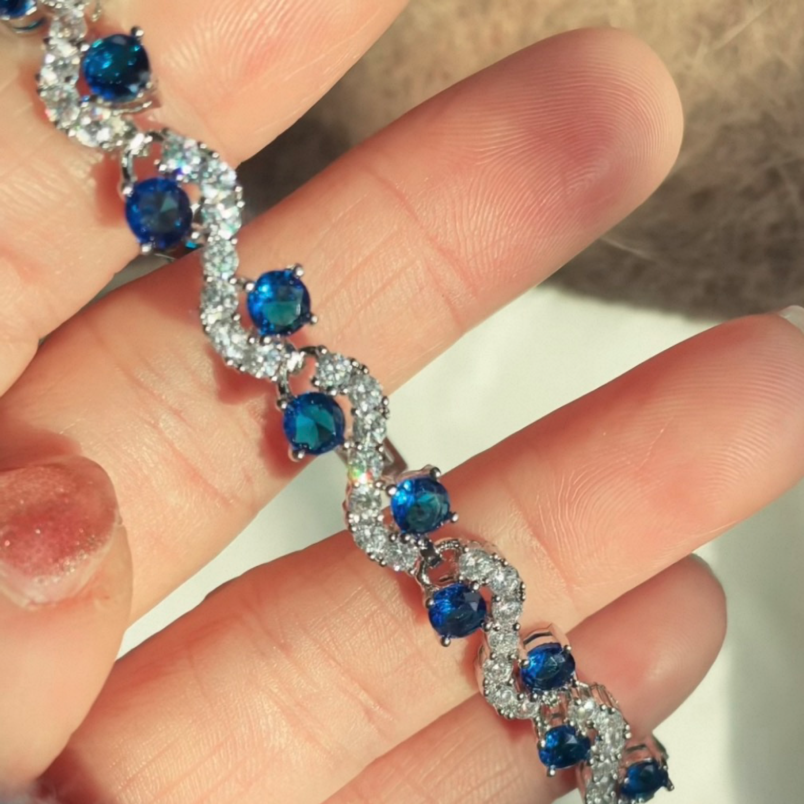 Bracelet with blue gemstones and clear stones held by a hand