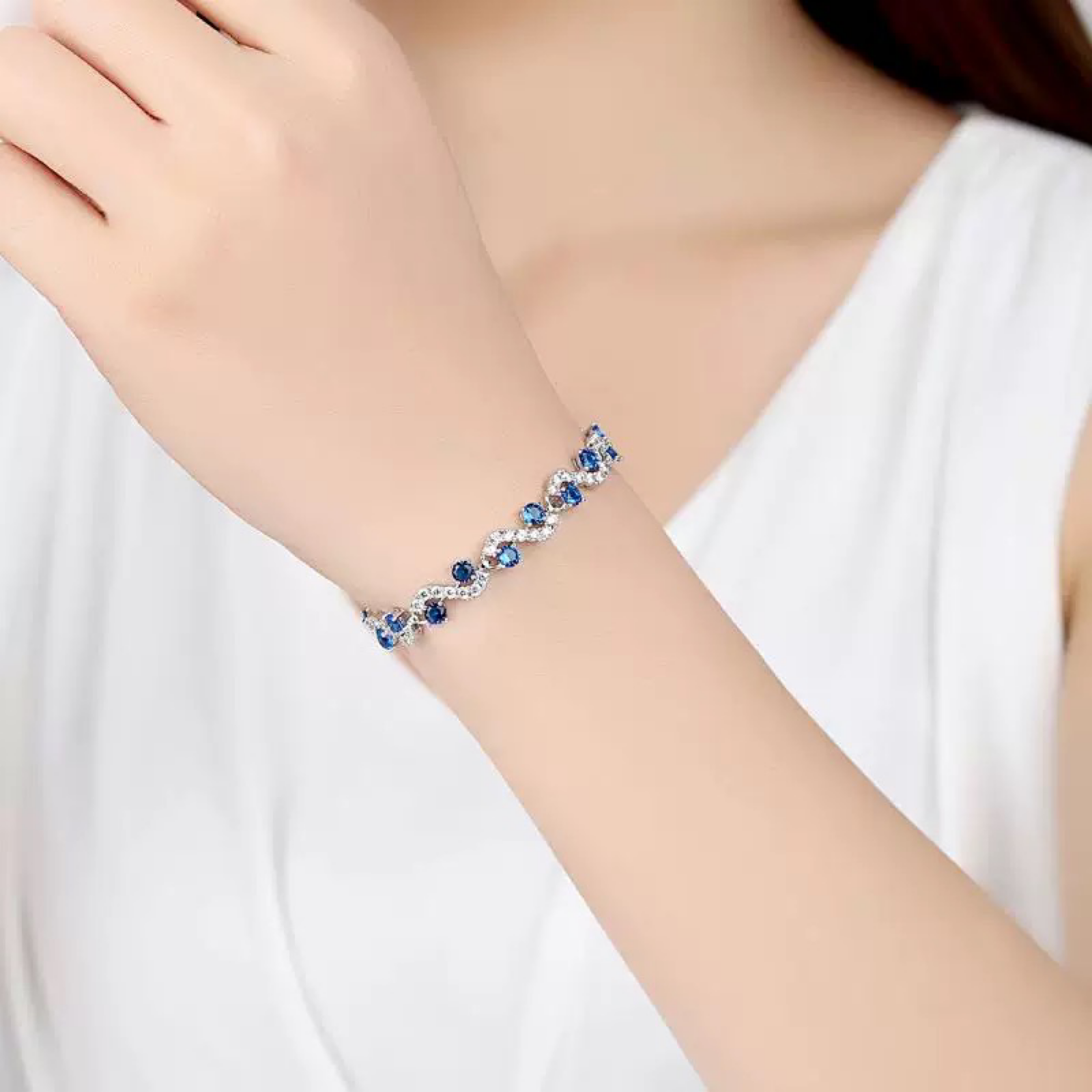 Bracelet with blue stones on a person's wrist against a white background
