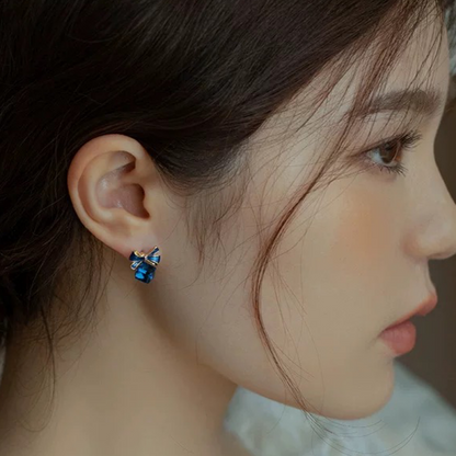 Close-up of a person wearing blue earrings with a blurred background