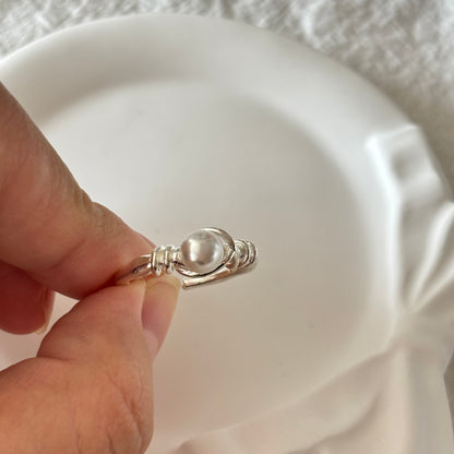 Enchanted Silver Pearl Ring Light Luxury Romantic Gift Women held between fingers on white background